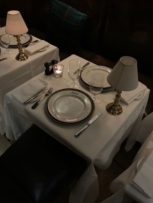 A beautifully set table in an elegant restaurant with sophisticated tableware and dim lighting.