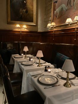 A cozy, vintage restaurant interior featuring elegant dinnerware and classic lighting.