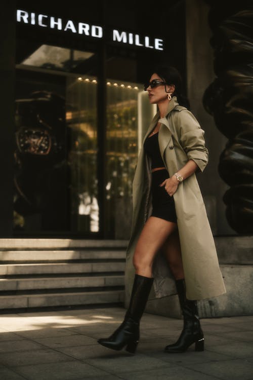Woman in Beige Trench Coat and Black Leather Boots Walking on a City Street