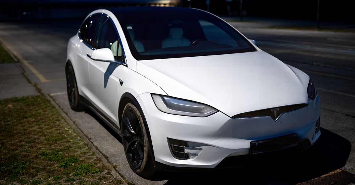 A white electric vehicle parked on an empty street in Garešnica at night.