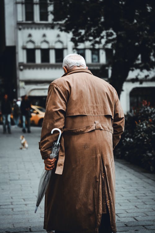 Elderly Man Walking with an Umbrella in Hand