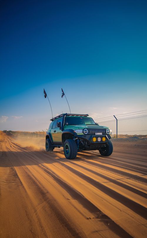Free A jeep drives across the sandy terrain in the Dubai desert, showcasing an adventurous spirit. Stock Photo