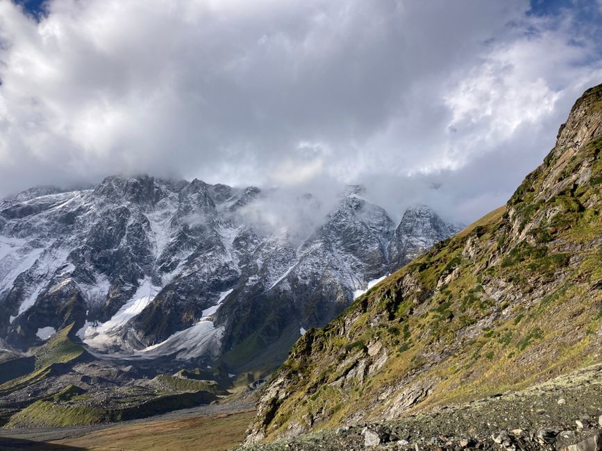 Breathtaking view of a rocky mountain range partially covered in snow under a cloudy sky.