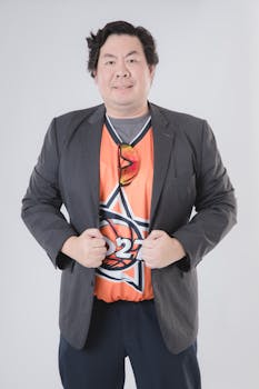 Portrait of a man in a blazer wearing an orange sports jersey with sunglasses.