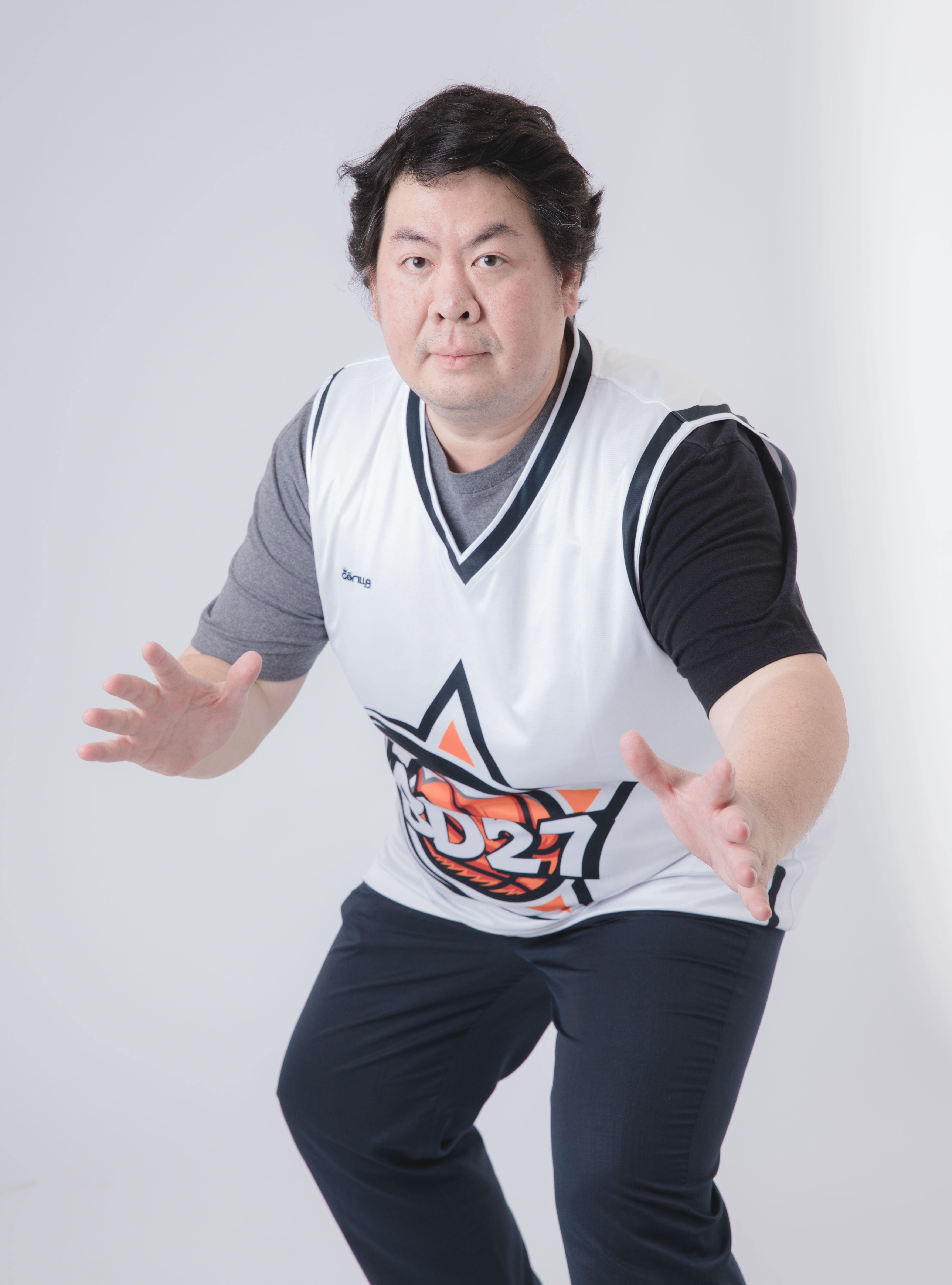 Man posing in sportswear with a basketball jersey indoors. Casual fashion meets athletic style.