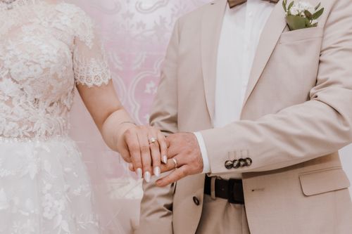 Free Close-up of a couple holding hands at their wedding, showcasing rings and elegant attire. Stock Photo