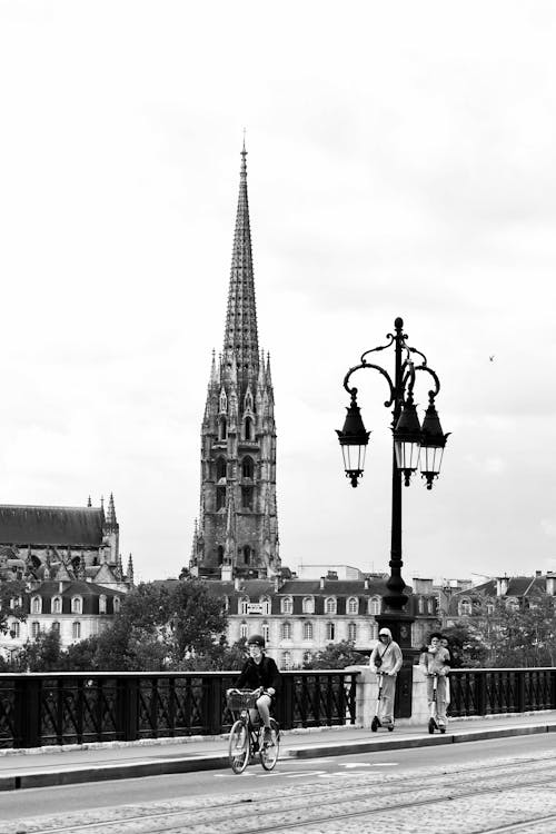 Black and White Photohgraph of a Cathedral Tower, and a Lampost on a Bridge