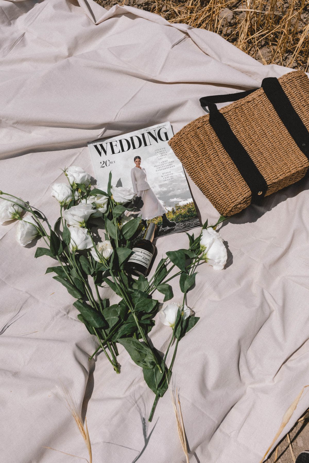White flowers, a bag and a book on a picnic blanket — the slow afternoon