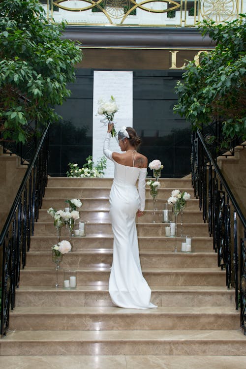 Bride in Wedding Dress Standing on Stairs with Flowers Decoration