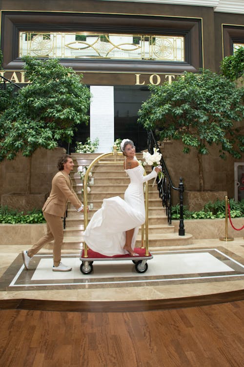 Groom Pushing Luggage Hotel Cart with Bride