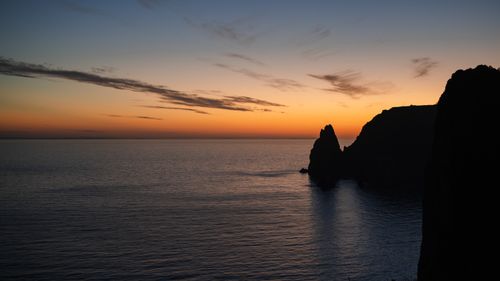 Free Captivating sunset over a rocky coastal seascape with vibrant sky and calm sea. Stock Photo