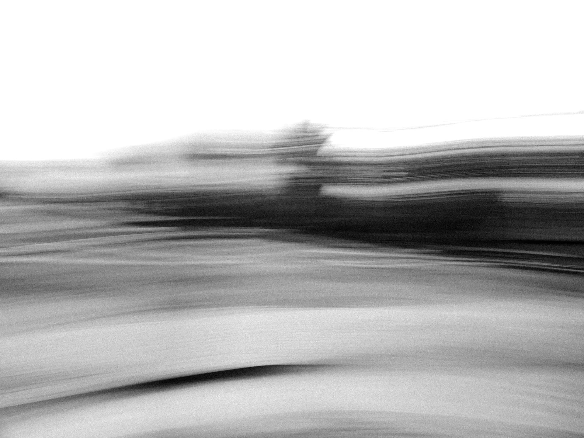 Abstract black and white image with blurred horizontal motion creating dynamic flow.