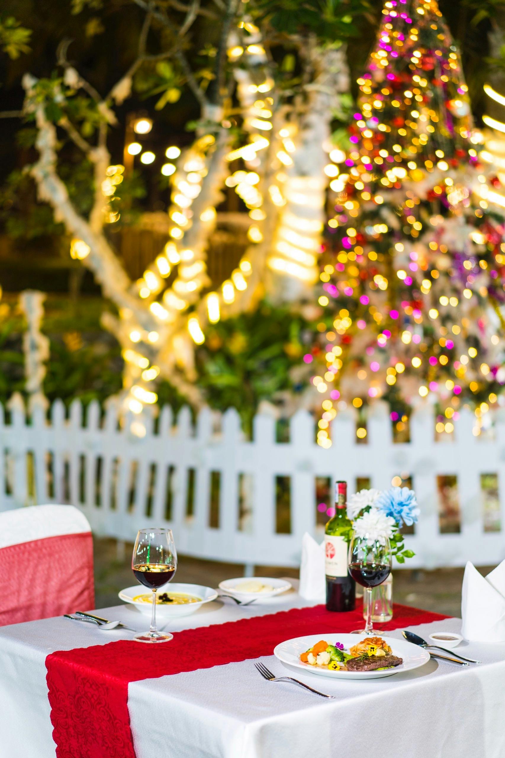 Intimate dining table set outdoors with wine and festive holiday decorations.