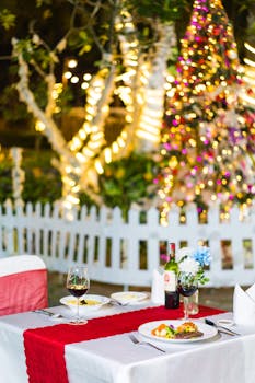 Intimate dining table set outdoors with wine and festive holiday decorations.