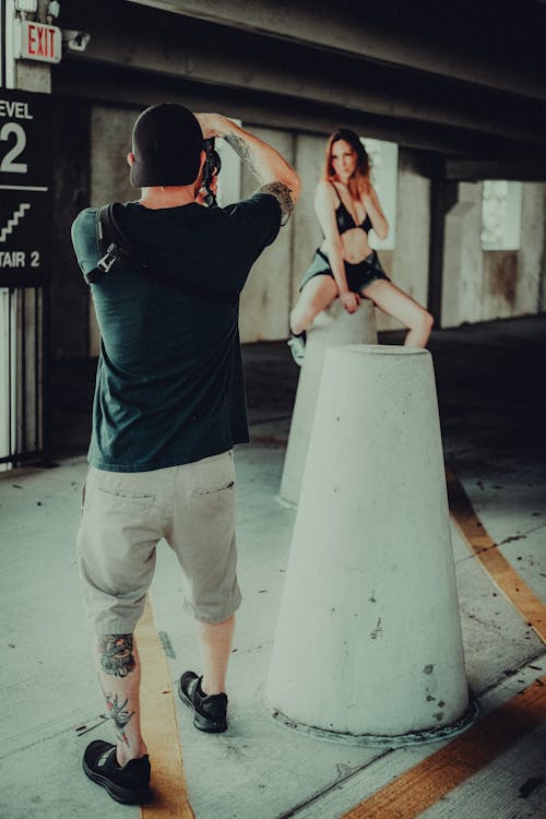 Man Photographing Woman which is Sitting on Concrete Urban Post