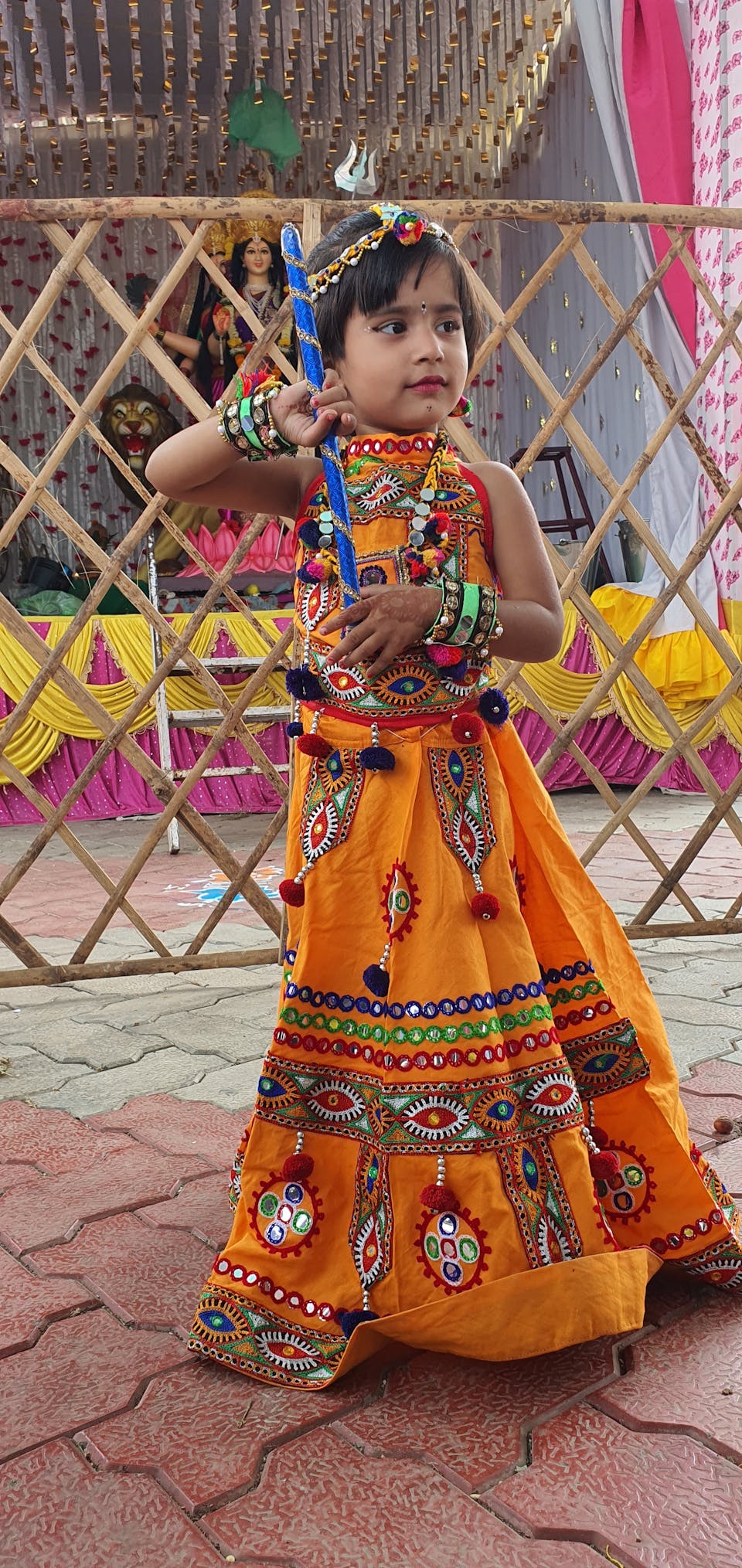 Girl in an ornate orange lehenga standing proudly near a festive altar