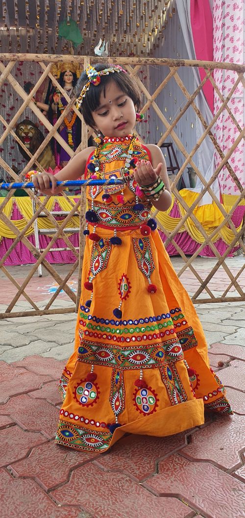 Free A young girl in vibrant traditional Indian clothing, holding sticks at a cultural event. Stock Photo