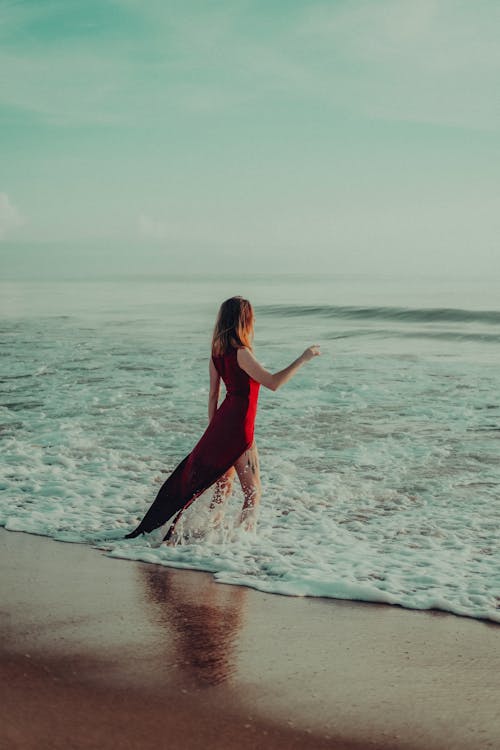 Model in a Red Dress Posing on the Seashore