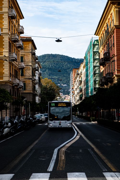Free A bus travels down a picturesque street lined with classic buildings in a European city. Stock Photo