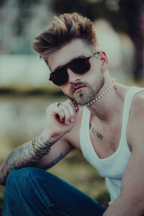 Tattooed Young Man in a Tank Top and a Pearl Necklace