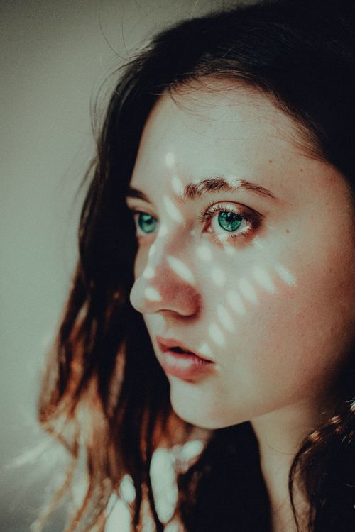 Free Artistic close-up portrait of a woman with dramatic light patterns across her face. Stock Photo