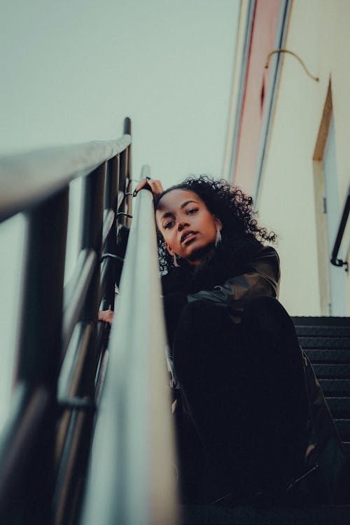 Low Angle Shot of a Young Woman Sitting on the Steps Outside 