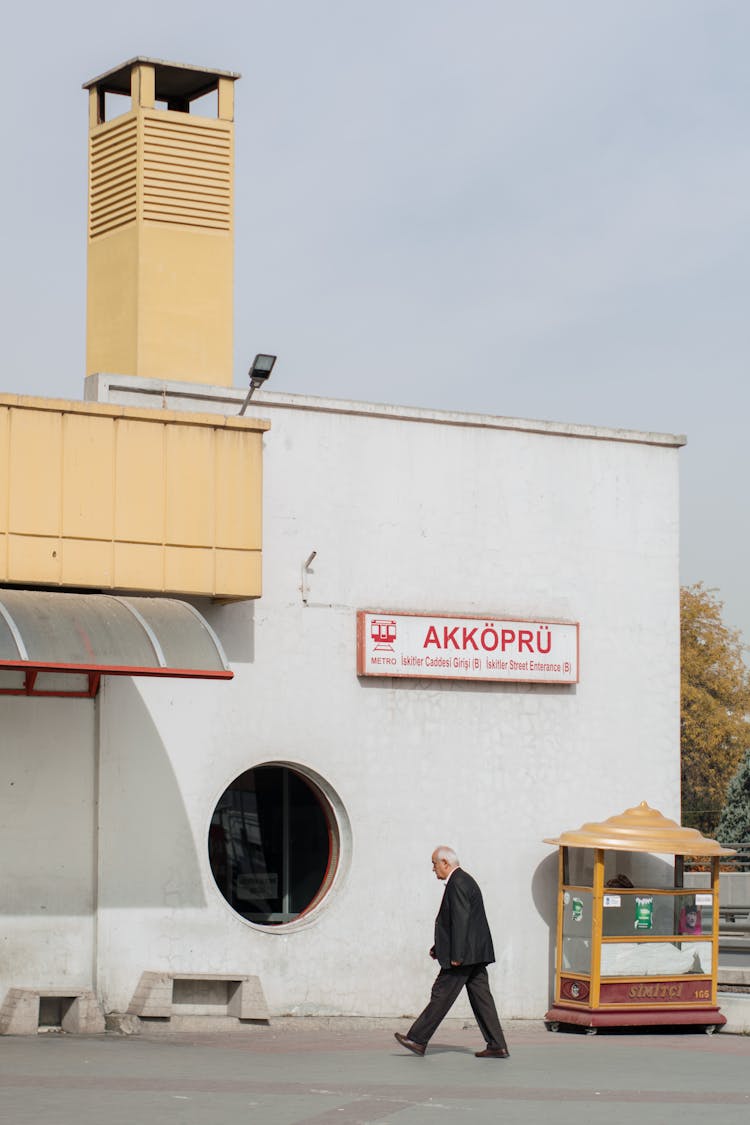 Candid Photo Of A Man Walking In Front Of A Building 