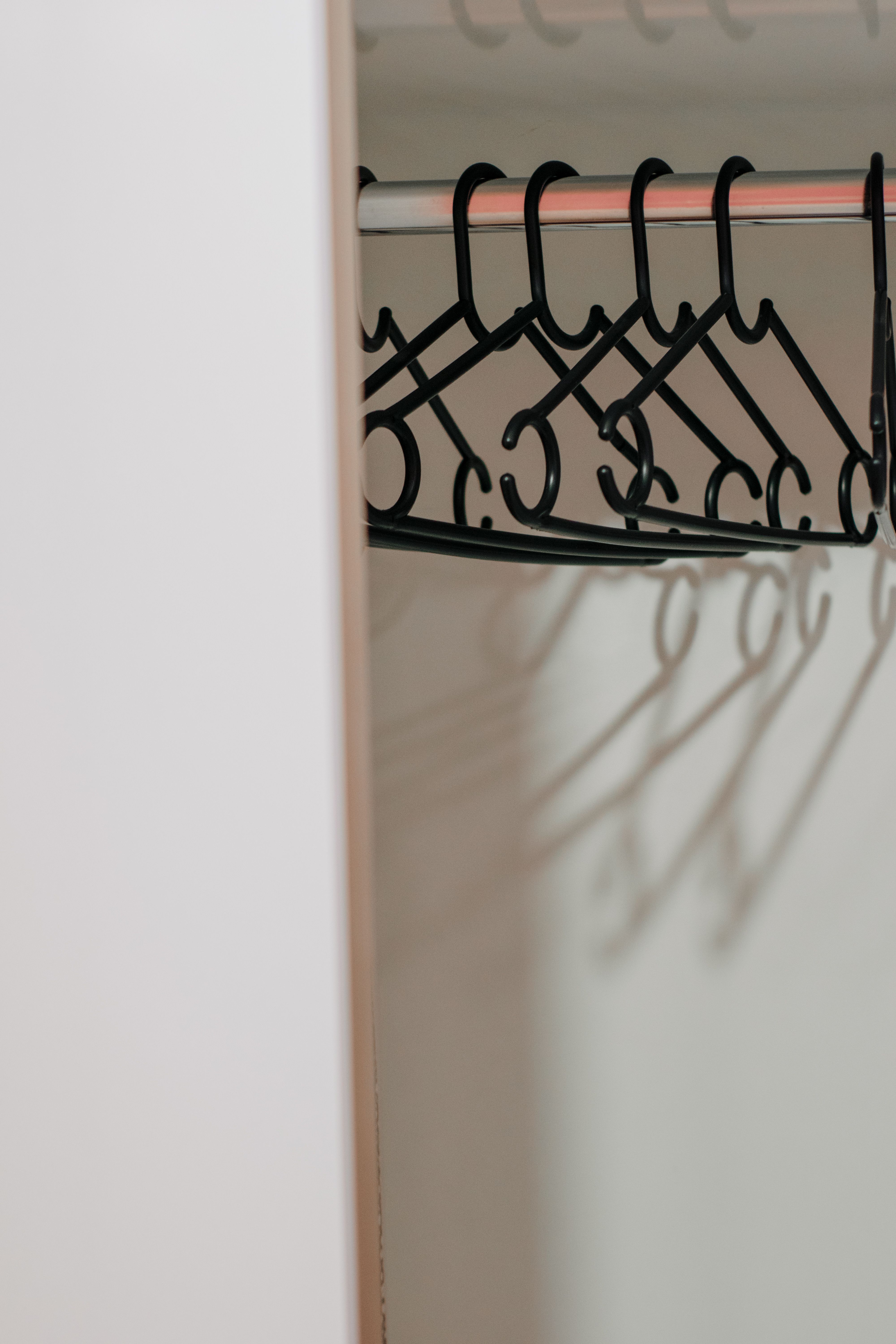 Minimalist view of black metal hangers in white closet interior.