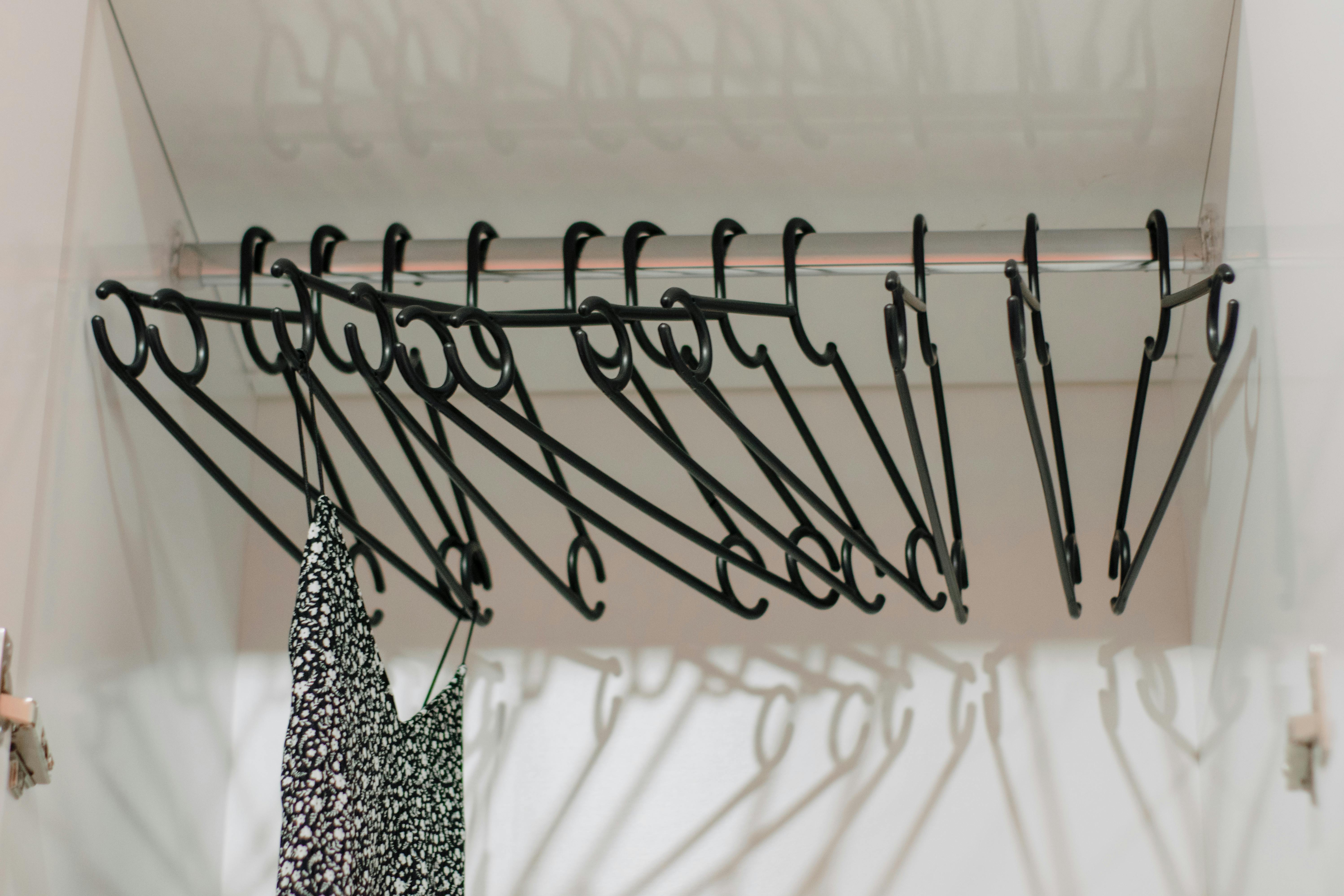 Minimalist closet interior with black hangers and a single patterned dress.