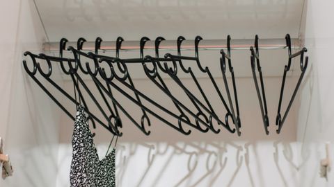 Minimalist closet interior with black hangers and a single patterned dress.