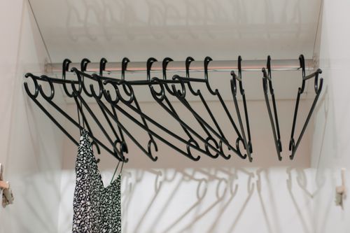 Free Minimalist closet interior with black hangers and a single patterned dress. Stock Photo