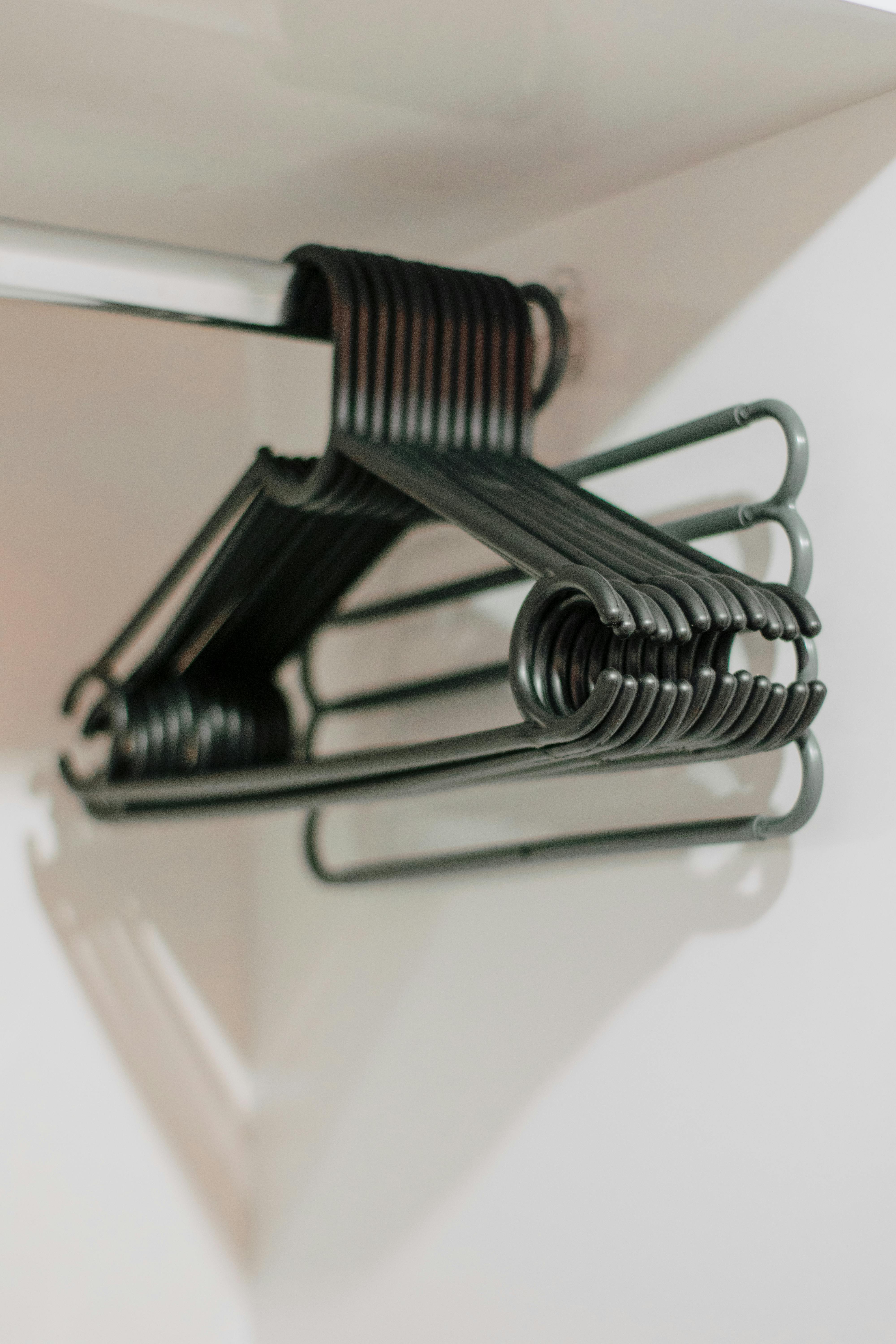 A stack of metal clothes hangers hanging in an empty closet wardrobe.