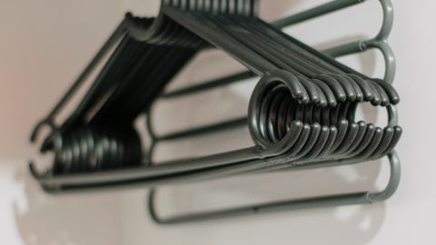 A stack of metal clothes hangers hanging in an empty closet wardrobe.