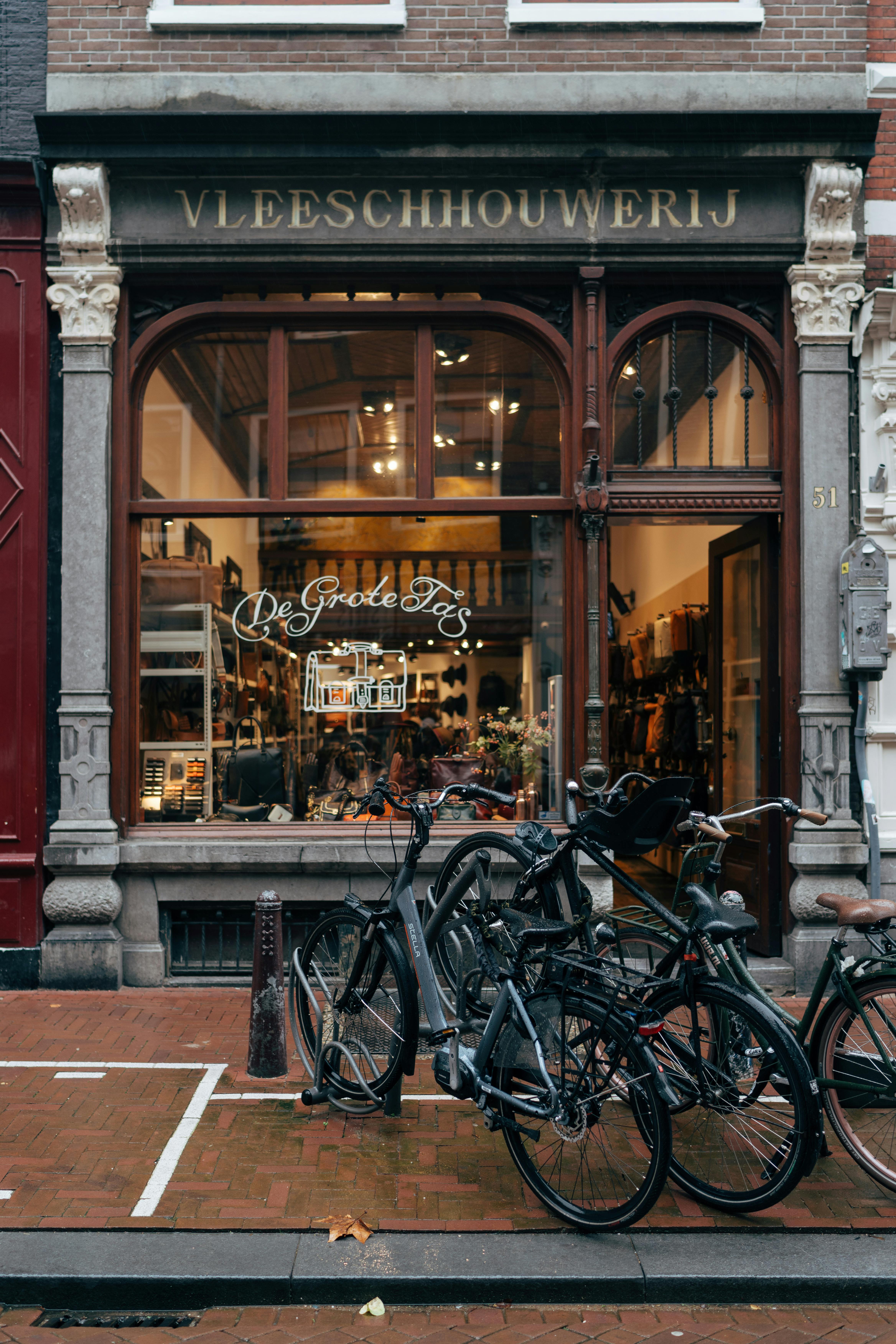 Classic Amsterdam scene with bicycles lined up outside a charming local shop on a cobblestone street.