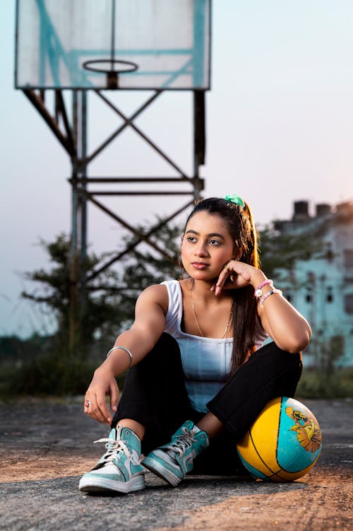 Young Woman Sitting on a Basketball Court Outside