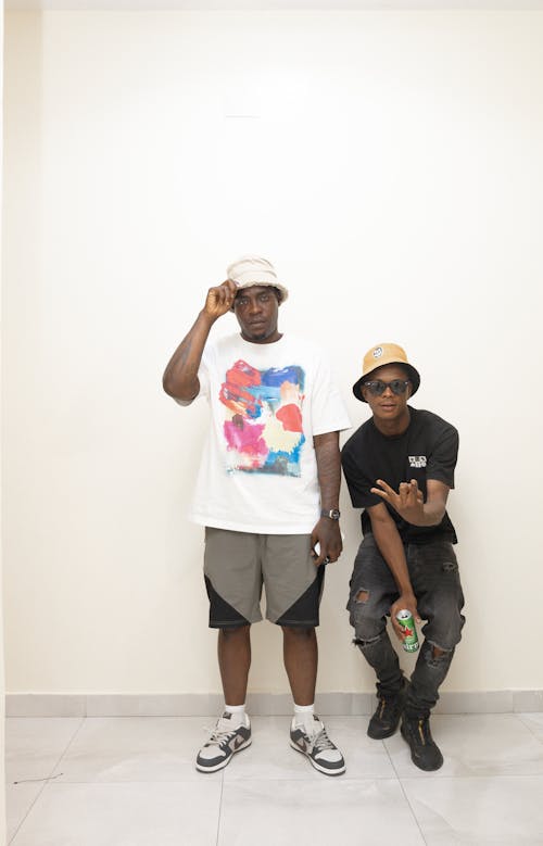 Young Men with Hats Posing by White Wall