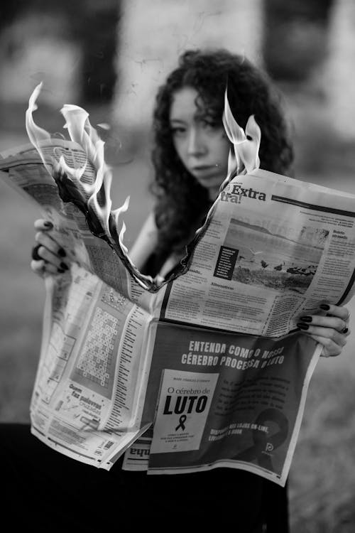 Woman Holding Burning Newspaper in Black and White