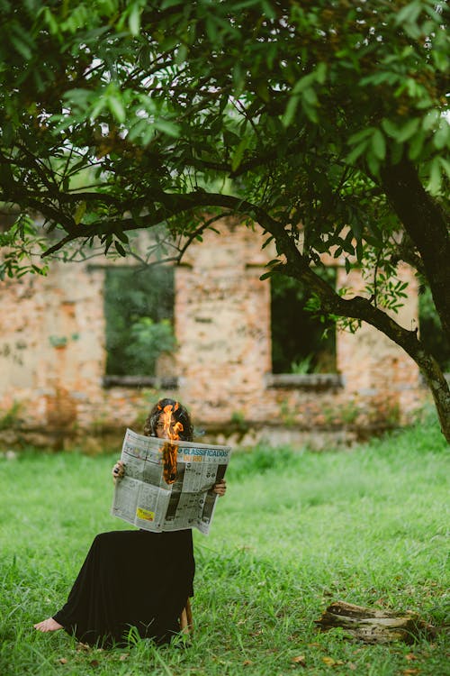 Woman Sitting Outside with a Burning Newspaper 