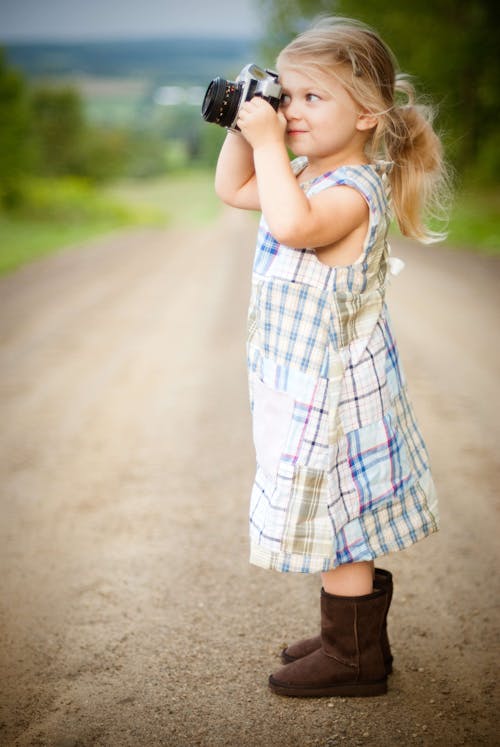 Menina Com Cabelo Loiro, Usando Vestido Xadrez Azul E Branco E Tirando Fotos Durante O Dia