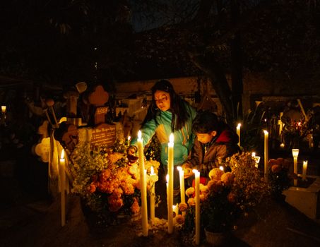 Captivating night scene of Día de Muertos with candles and traditions in a Mexican cemetery.