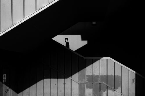 Free A striking black and white image of a person walking on stairs, highlighting modern architecture and shadows. Stock Photo
