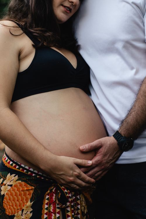 Free Close-up of an expecting couple embracing, highlighting the woman's pregnant belly and shared parental love. Stock Photo