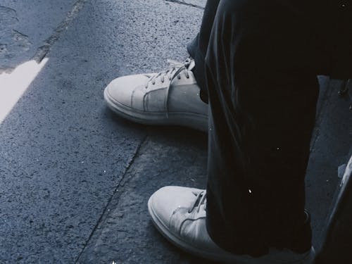 Close-up of Person in Sneakers Sitting on Street