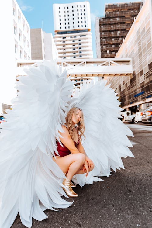 Model with Angel Wings Squatting and Posing on Street