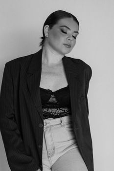 Black and white portrait of a stylish woman in a blazer, eyes closed, showcasing elegance.