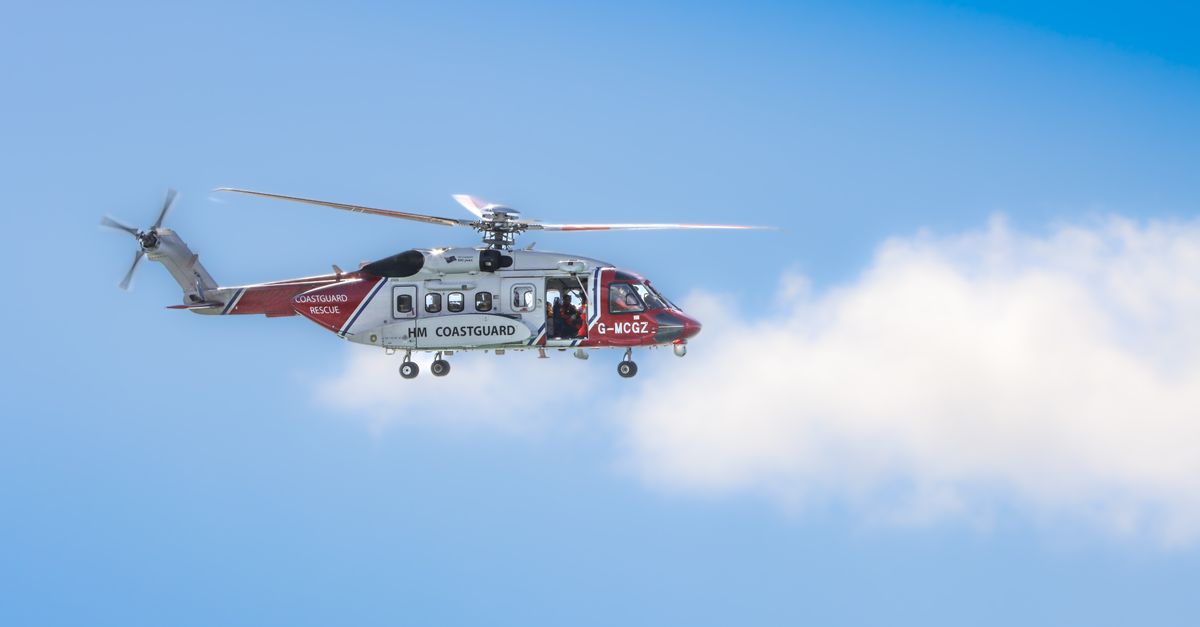 A Coast Guard helicopter flying against a blue sky during daytime patrol mission.