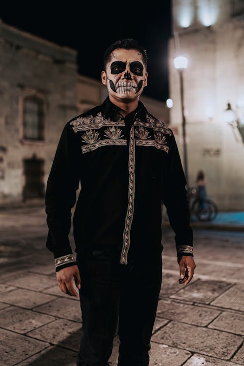 Portrait of a Man Wearing a Skull Face Paint Standing Outdoors at Night