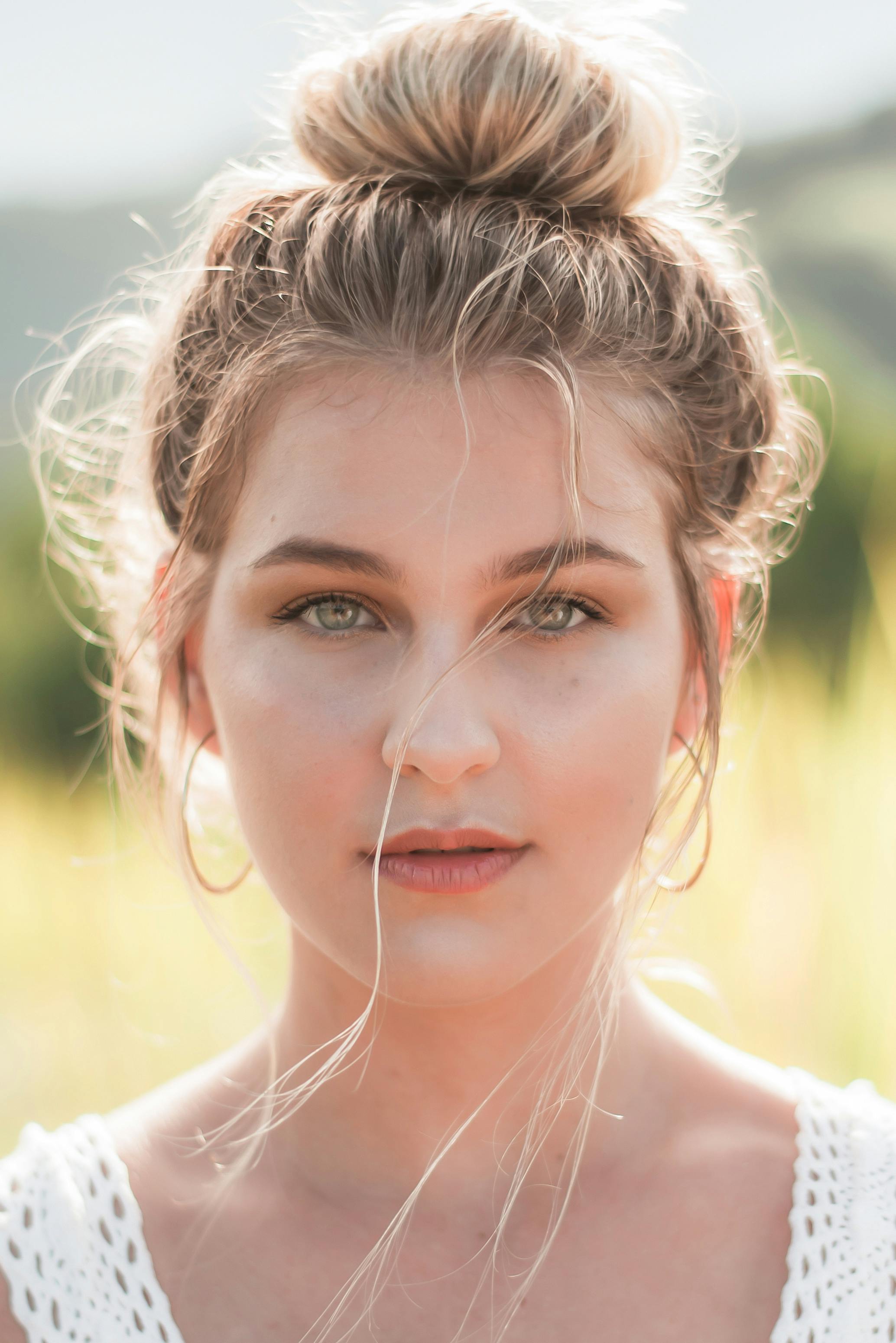 Woman With Bun Hair Wearing Hoop Earrings and White Knitted Tank Top