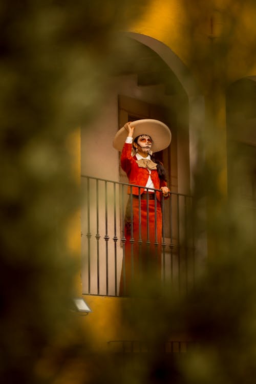 Catrina in Red Clothes and Sombrero Standing on Balcony