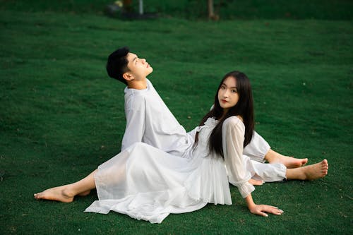 Woman in White Dress Sitting with Man on Grass